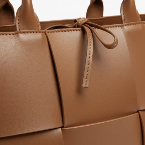 Close-up of Aurelia caramel genuine leather tote bag showcasing the woven leather texture and decorative tie closure