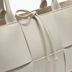 Close-up of Aurelia off-white genuine leather tote bag showcasing the woven texture and decorative tie closure