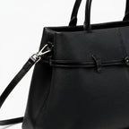 Close-up of the black genuine leather tote bag featuring a stylish buckle design and high-quality stitching with a detachable shoulder strap