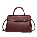 Front view of a wine red genuine leather tote bag with a sleek and sophisticated design, highlighted by the central buckle accent