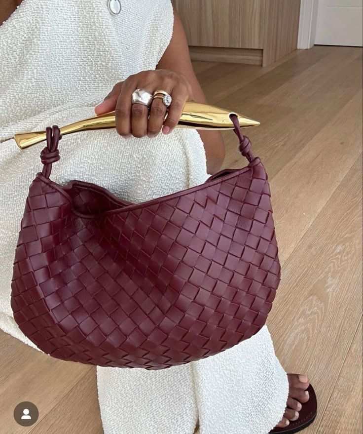 Noémie burgundy woven vegan leather handbag with gold-tone hardware held by a person in white