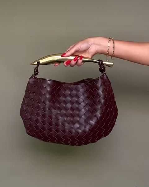 Noémie woven vegan leather handbag with gold-tone stainless steel handle held against a plain background