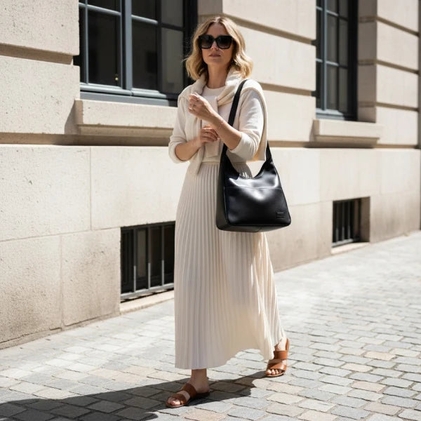 Model carrying Seliora vegan leather shoulder bag in black while walking outdoors in casual outfit