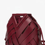 Seren Vegan Leather Bucket Bag in wine red, closeup highlighting triangular top handle, wide woven straps, and drawstring opening