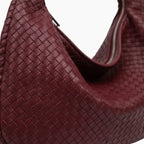 Close-up of wine red woven vegan leather hobo bag showcasing the intricate weave pattern and smooth texture